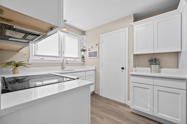 kitchen with white cabinets, light wood-type flooring, decorative light fixtures, and sink