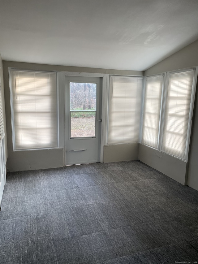 carpeted empty room with vaulted ceiling