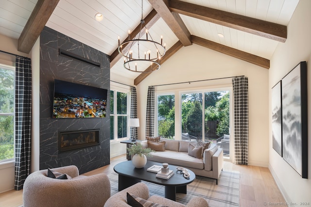 living room featuring baseboards, lofted ceiling with beams, a premium fireplace, wood finished floors, and an inviting chandelier