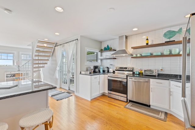 kitchen featuring plenty of natural light, white cabinets, range hood, and appliances with stainless steel finishes