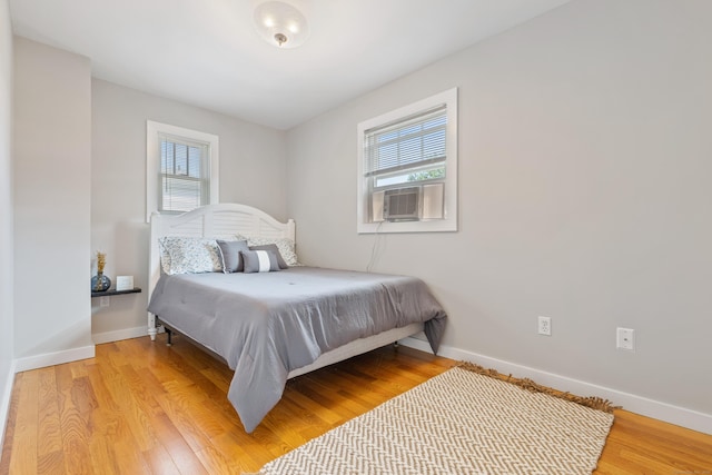 bedroom featuring cooling unit, light wood-type flooring, and multiple windows