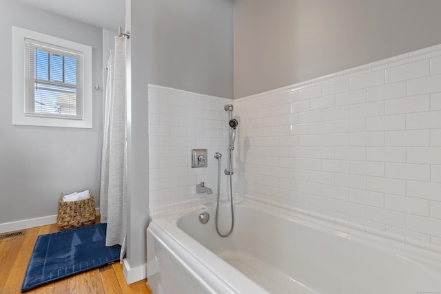 bathroom with a washtub and wood-type flooring