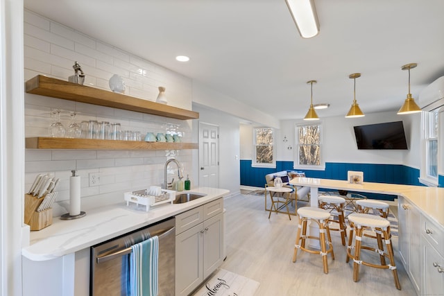 kitchen with sink, hanging light fixtures, stainless steel dishwasher, light stone countertops, and white cabinetry