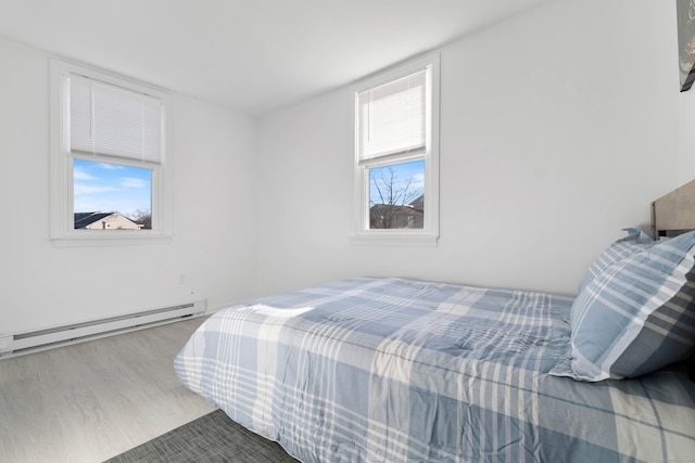 bedroom with a baseboard radiator and light wood-type flooring