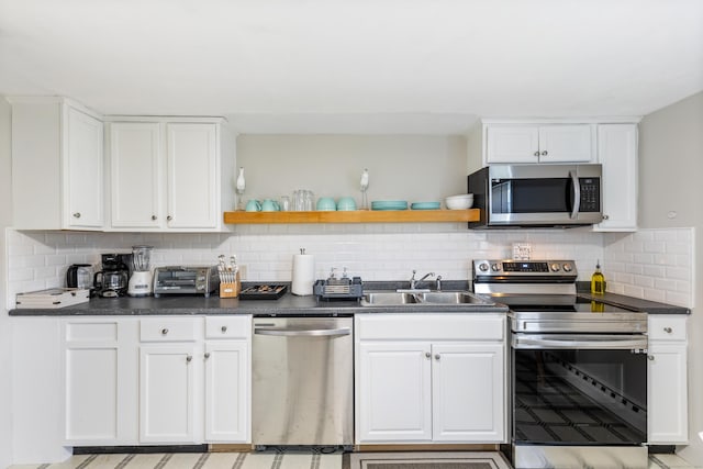 kitchen featuring appliances with stainless steel finishes, tasteful backsplash, white cabinetry, and sink