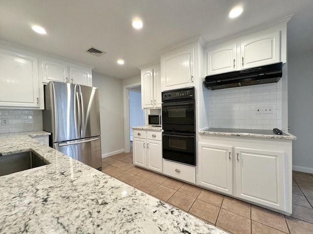 kitchen featuring decorative backsplash, light stone countertops, stainless steel appliances, light tile patterned floors, and white cabinets