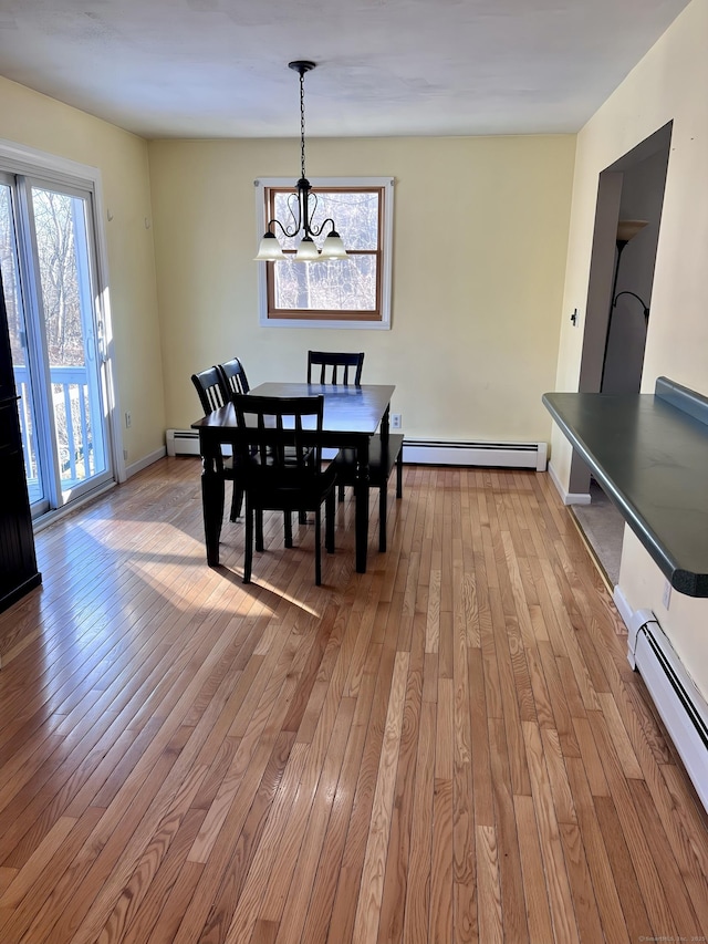 dining area with light wood-type flooring, a chandelier, and baseboard heating