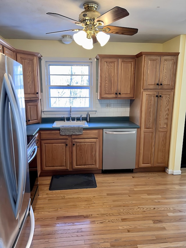 kitchen featuring sink, decorative backsplash, ceiling fan, stainless steel appliances, and light hardwood / wood-style flooring