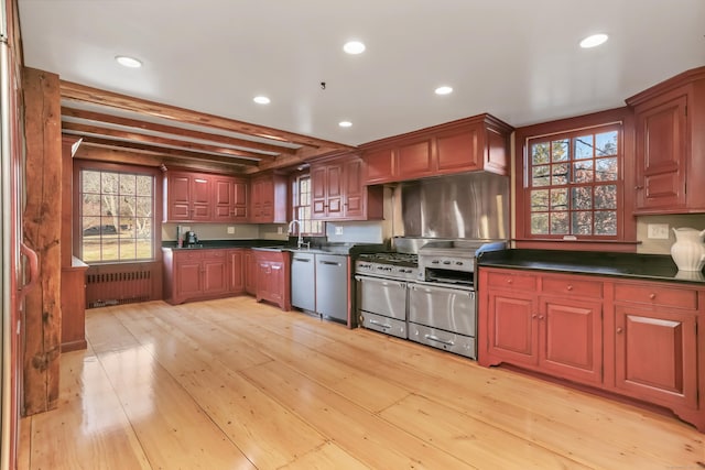 kitchen featuring light wood-style flooring, recessed lighting, stainless steel dishwasher, radiator, and dark countertops