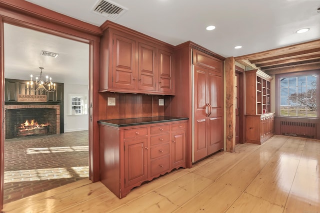 kitchen with a fireplace, visible vents, light wood-style floors, radiator, and dark countertops