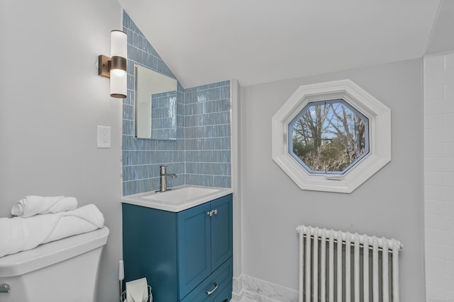 bathroom featuring lofted ceiling, toilet, vanity, and radiator