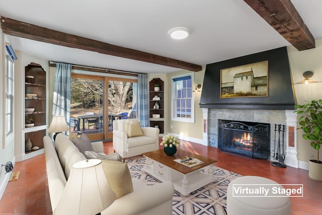 living area featuring baseboards, a tiled fireplace, and beamed ceiling