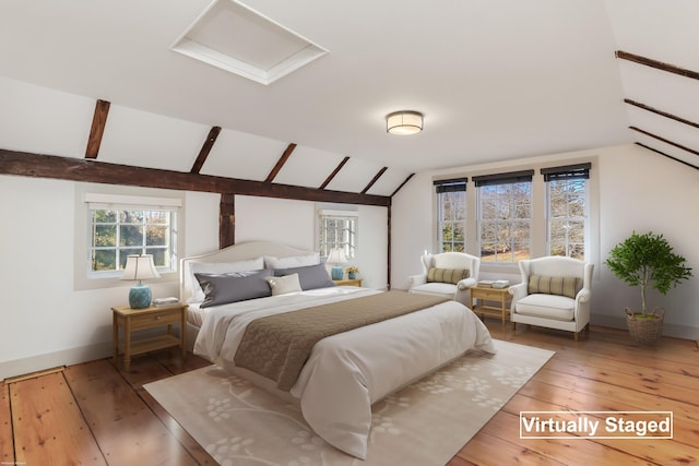 bedroom featuring light wood finished floors, attic access, baseboards, and vaulted ceiling