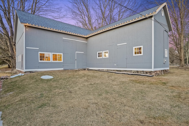 rear view of property with a yard and roof with shingles