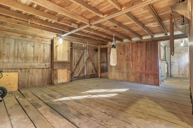 misc room with a barn door, wood-type flooring, and wooden walls