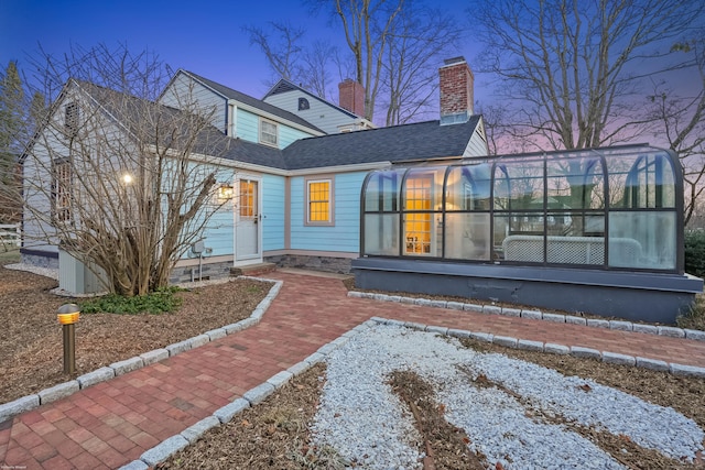 rear view of property with a shingled roof and a chimney