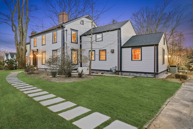 back of house featuring a chimney, central AC, and a yard