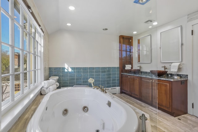 bathroom with a sink, visible vents, vaulted ceiling, a jetted tub, and double vanity