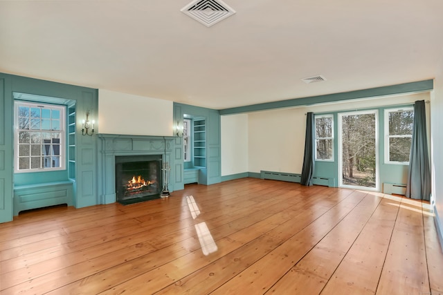 unfurnished living room featuring a warm lit fireplace, light wood-style flooring, baseboard heating, and visible vents