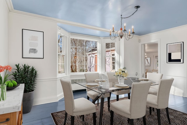 dining space featuring an inviting chandelier, wood finished floors, and crown molding