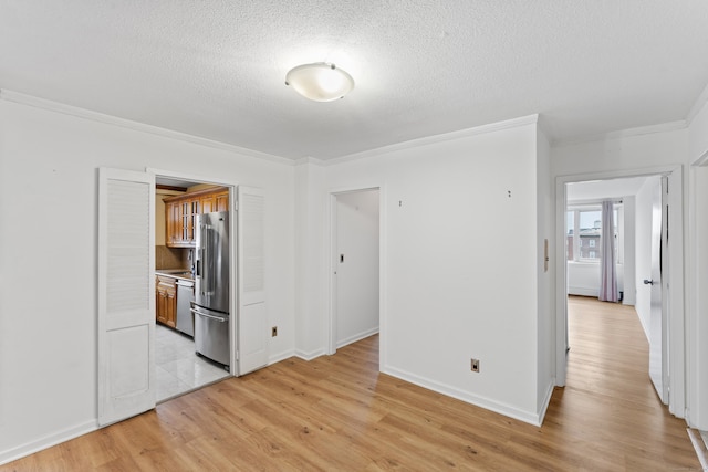 empty room featuring a textured ceiling, light hardwood / wood-style flooring, and crown molding