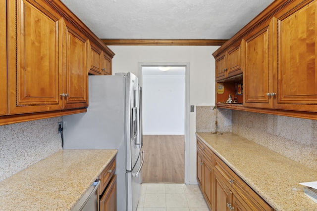 kitchen with light stone counters, white refrigerator with ice dispenser, crown molding, decorative backsplash, and light tile patterned flooring