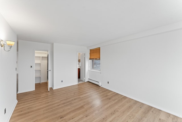 interior space featuring light hardwood / wood-style floors, a spacious closet, baseboard heating, and a closet