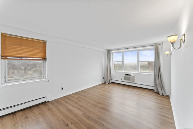 spare room with a wall mounted air conditioner, light wood-type flooring, and a baseboard radiator