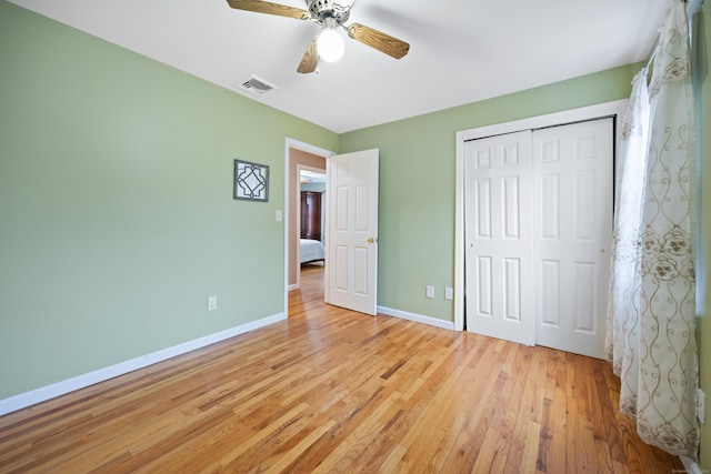 unfurnished bedroom featuring ceiling fan, light wood-type flooring, and a closet