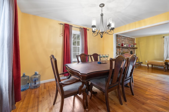 dining room with hardwood / wood-style floors, a brick fireplace, and a chandelier