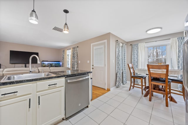 kitchen with white cabinetry, sink, hanging light fixtures, stainless steel dishwasher, and light tile patterned flooring