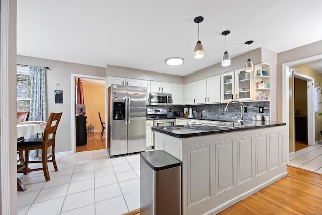 kitchen with kitchen peninsula, white cabinetry, sink, and appliances with stainless steel finishes