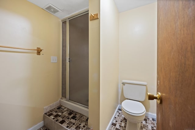 bathroom featuring a shower with door and toilet