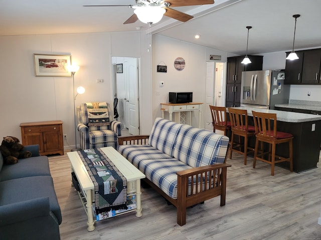 living room with lofted ceiling, ceiling fan, and light wood finished floors