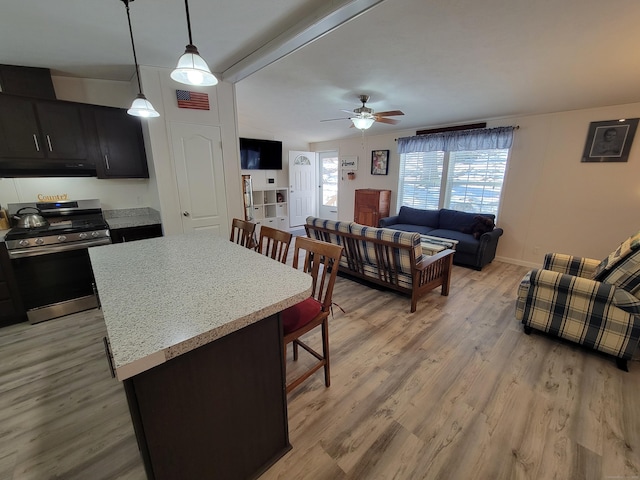 kitchen featuring stainless steel gas range oven, visible vents, open floor plan, decorative light fixtures, and under cabinet range hood