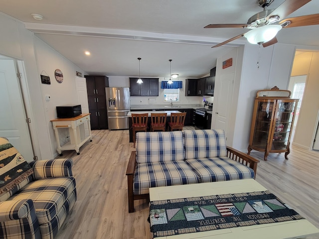 living area featuring lofted ceiling with beams, plenty of natural light, and light wood-style flooring