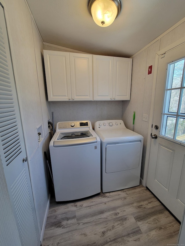 washroom with cabinet space, washing machine and dryer, and light wood-style flooring