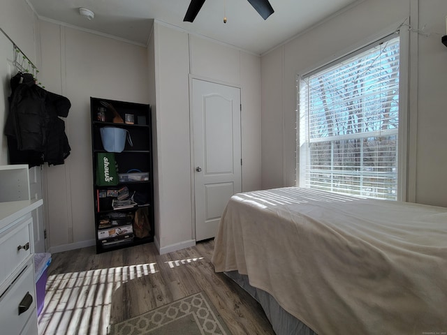 bedroom with dark wood-style floors, ornamental molding, baseboards, and ceiling fan