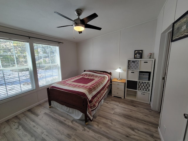 bedroom featuring ceiling fan, ornamental molding, light wood-type flooring, and baseboards