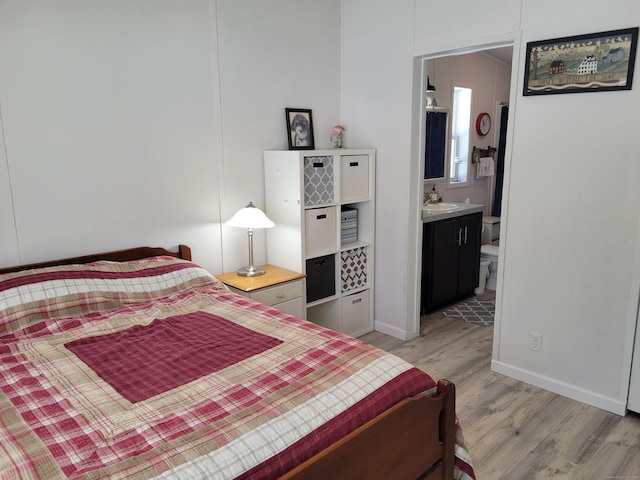 bedroom with a sink, light wood-style floors, baseboards, and connected bathroom