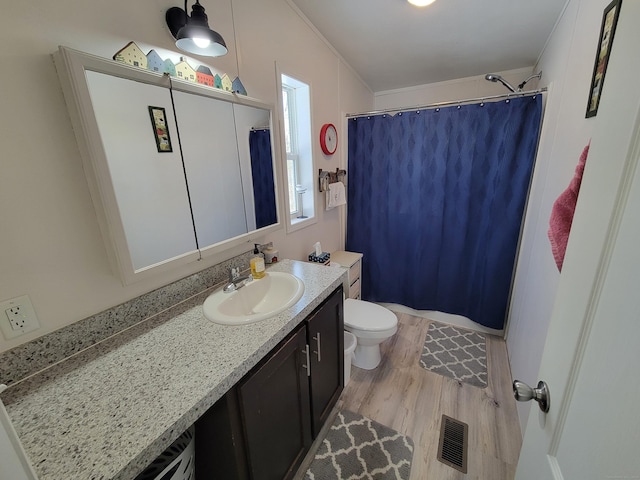 bathroom with toilet, wood finished floors, visible vents, vanity, and ornamental molding