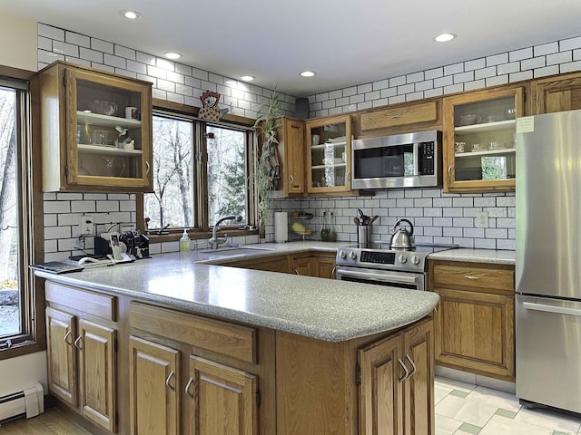 kitchen featuring sink, baseboard heating, appliances with stainless steel finishes, and tasteful backsplash