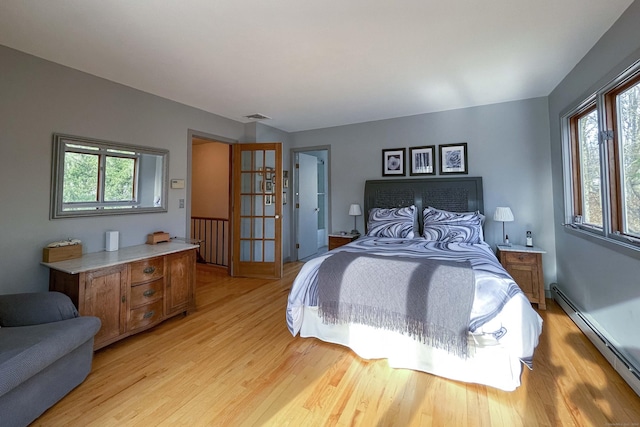 bedroom featuring baseboard heating, multiple windows, and light hardwood / wood-style flooring