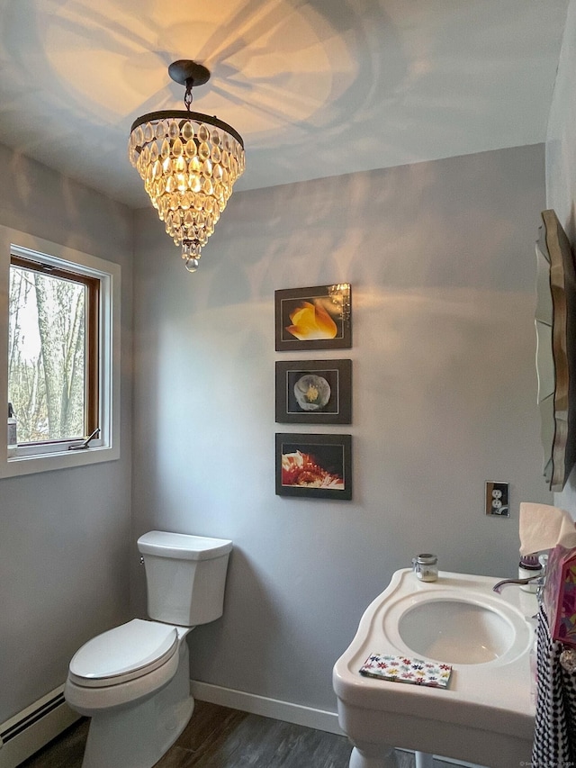 bathroom with a baseboard heating unit, sink, hardwood / wood-style flooring, toilet, and a chandelier