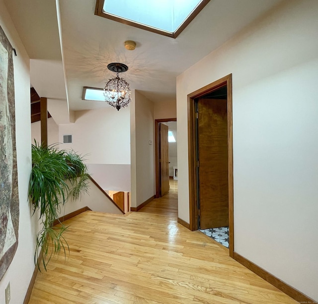 hall with light hardwood / wood-style flooring and a notable chandelier