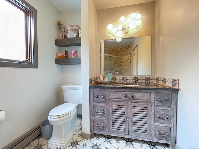 bathroom with a tile shower, vanity, toilet, and a baseboard heating unit