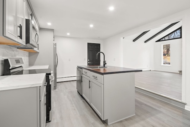 kitchen featuring gray cabinetry, sink, light hardwood / wood-style flooring, range, and an island with sink