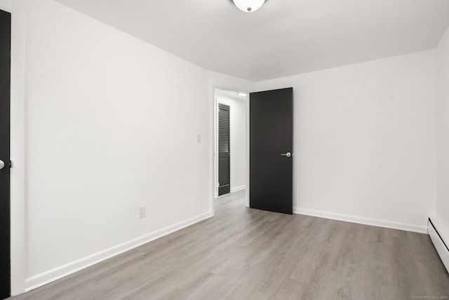 unfurnished room featuring light hardwood / wood-style floors and a baseboard radiator