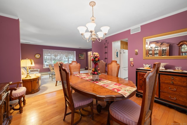 dining space with light hardwood / wood-style flooring, crown molding, and a chandelier