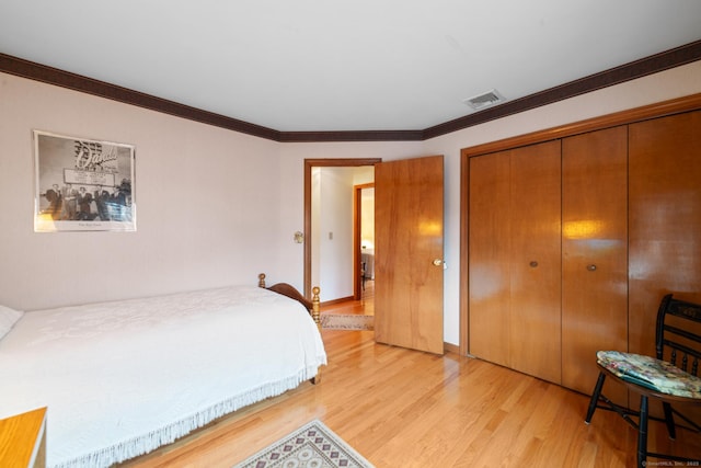 bedroom with a closet, ornamental molding, and light hardwood / wood-style floors